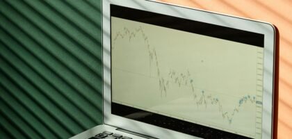 A laptop displaying financial graphs with documents on a sunlit office desk, ideal for finance themes.