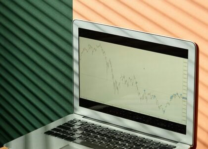 A laptop displaying financial graphs with documents on a sunlit office desk, ideal for finance themes.